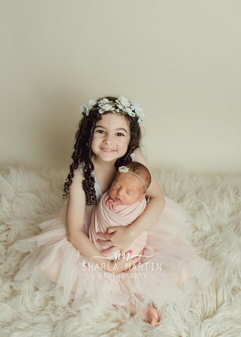 sibling posing with newborn baby and big sister wearing flower crown austin