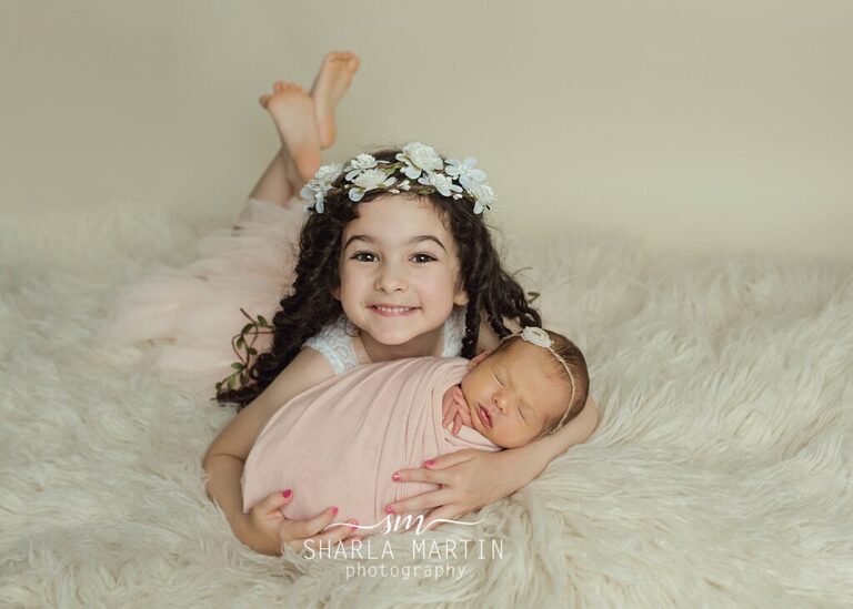 big sister holding baby sister smiling