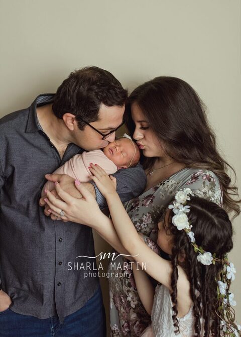 family picture mom and dad kissing newborn baby girl