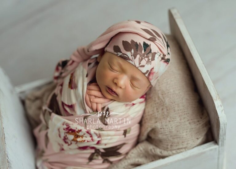 newborn baby wrapped in wooden bed