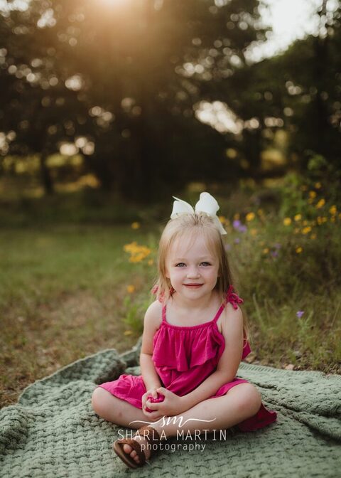 little girl smiling with flowers at park in cedar park