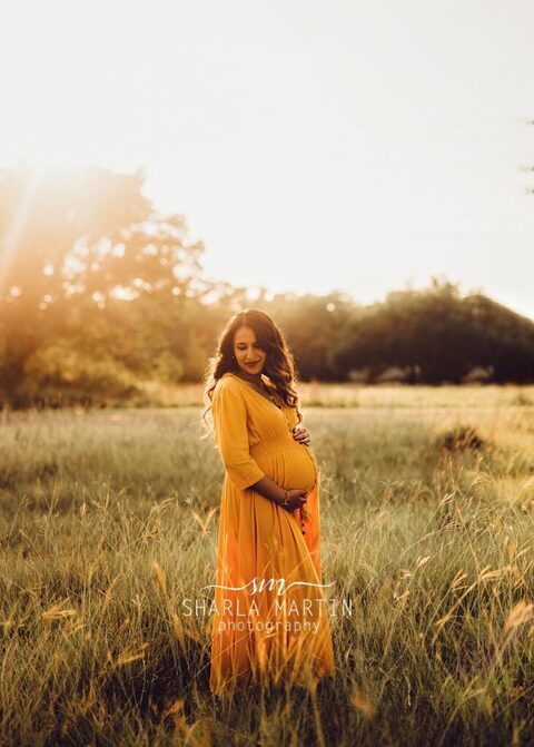 beautiful pregnant mama with sun lighting hair in field