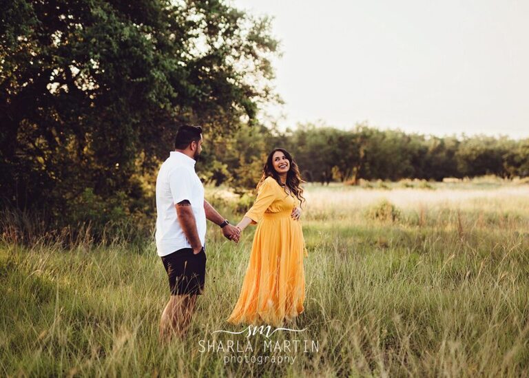 Maternity couple walking in field laughing