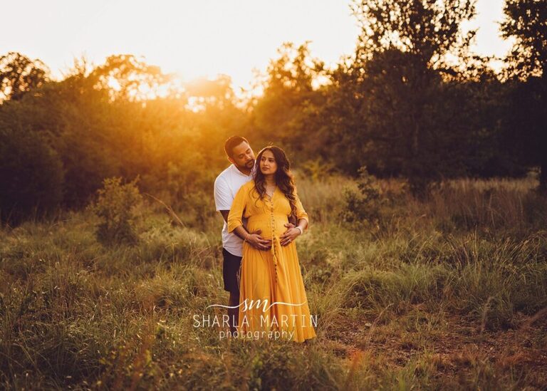 maternity couple taking pictures in field