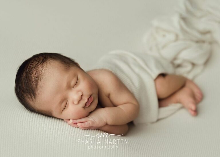 Newborn sleeping head on hands posed for baby photos