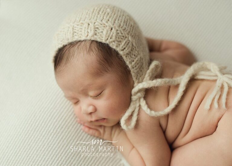 newborn baby boy sleeping with bonnet on for newborn photography session