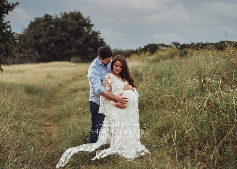 maternity photo session with couple smiling at belly in sunflower field austin tx