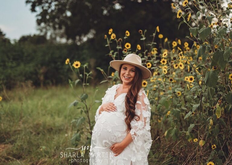 beautiful pregnant mother wearing hat in sunflower field for maternity photos austin