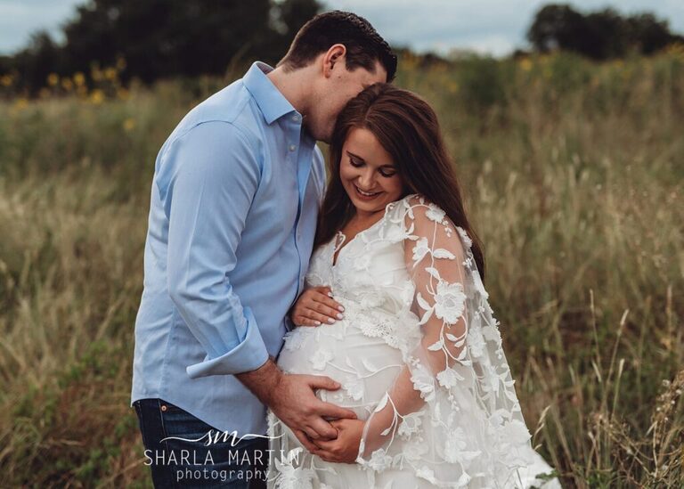 couple snuggling in field for maternity photo shoot in Austin