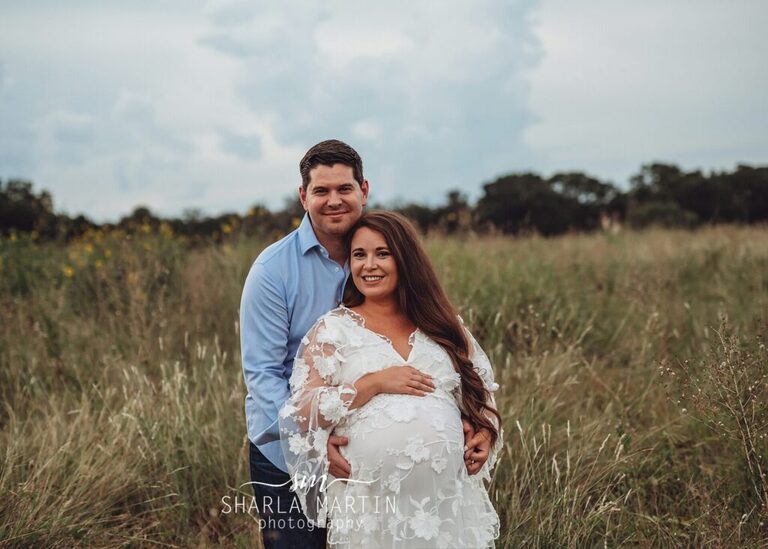 beautiful couple posing for maternity photos in field Cedar Park Texas